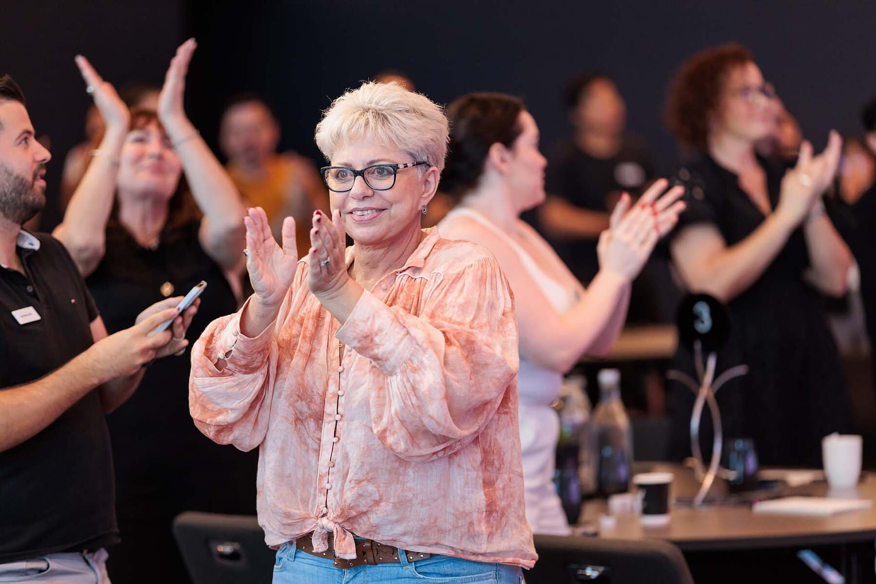 Participants clapping and celebrating at a leadership development event in Australia.
